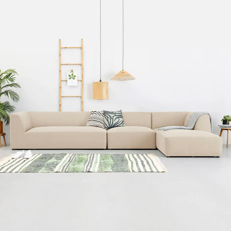 A contemporary living room featuring a stylish beige sectional sofa, complemented by modern decor and natural light.