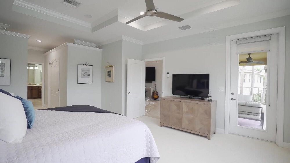 A stylish bedroom with a ceiling fan above and a television on the wall, perfect for leisure and comfort